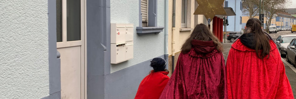 Sternsinger gehen eine Straße entlang.